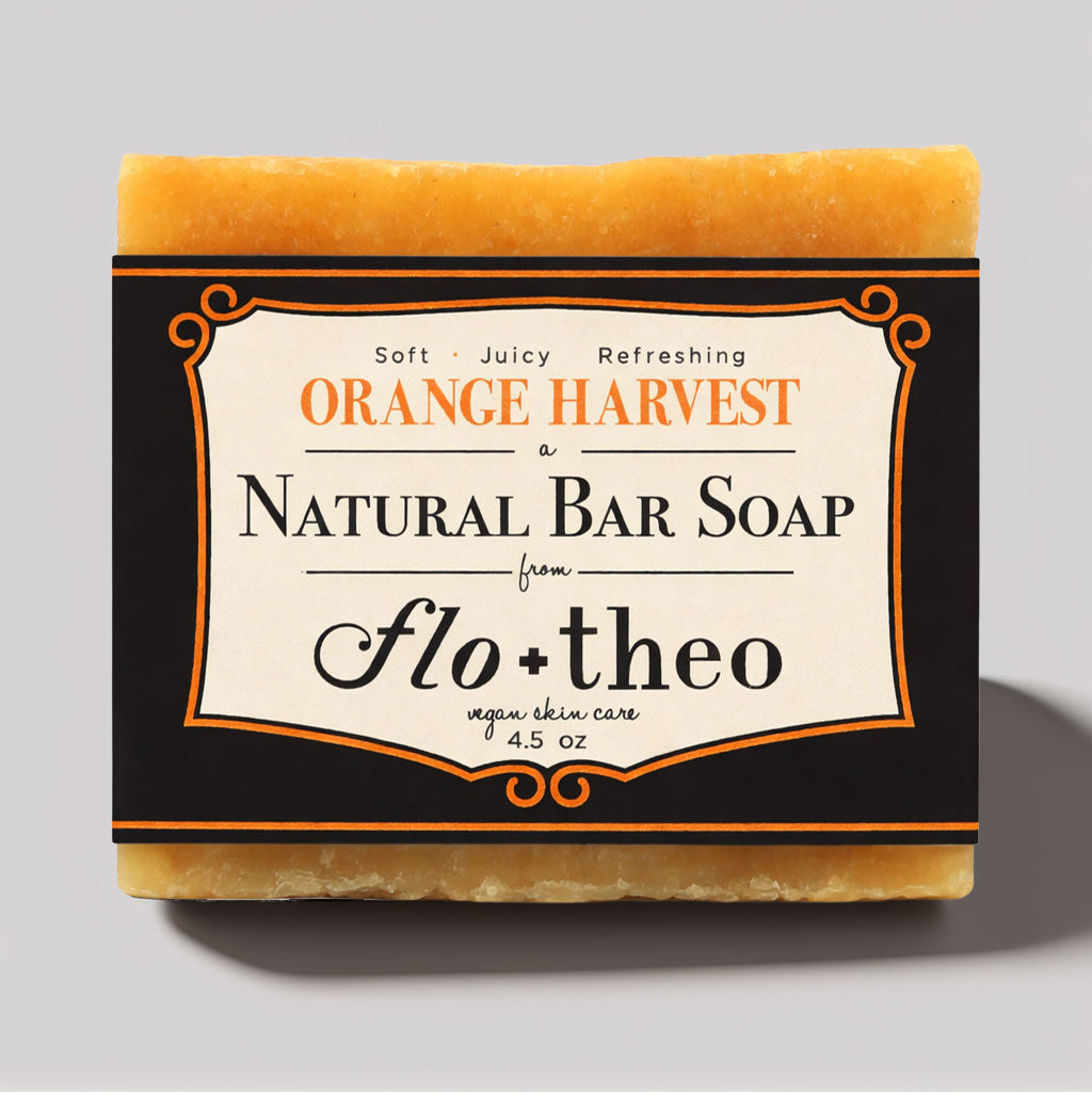 Bar of soap with 'Orange Harvest' and 'Flo + Theo' branding on a gray background